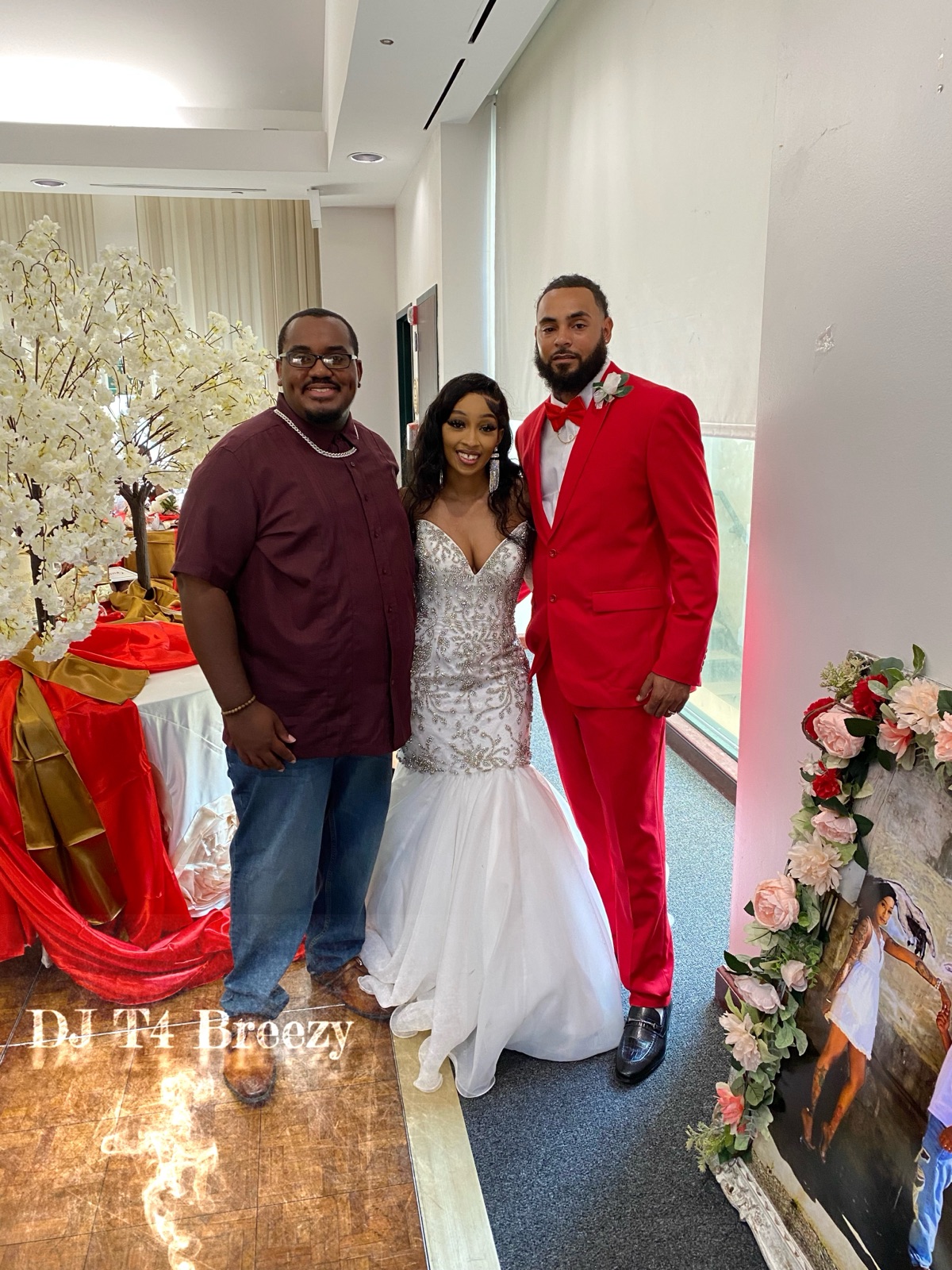 DJ T4 Breezy with a bride in a white gown and a groom in a red suit at a wedding reception